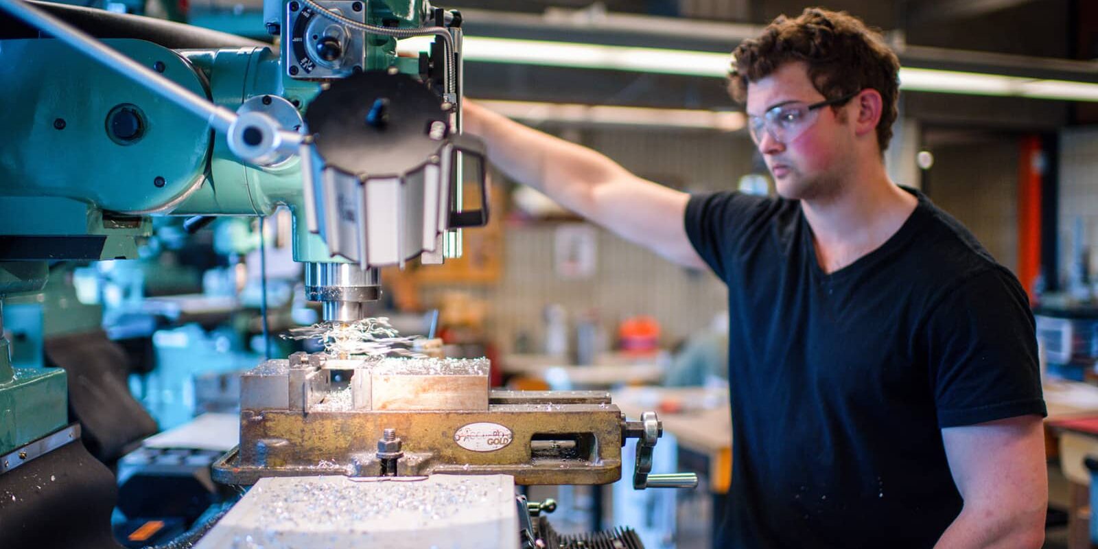 UMass engineering student operates a drill press.