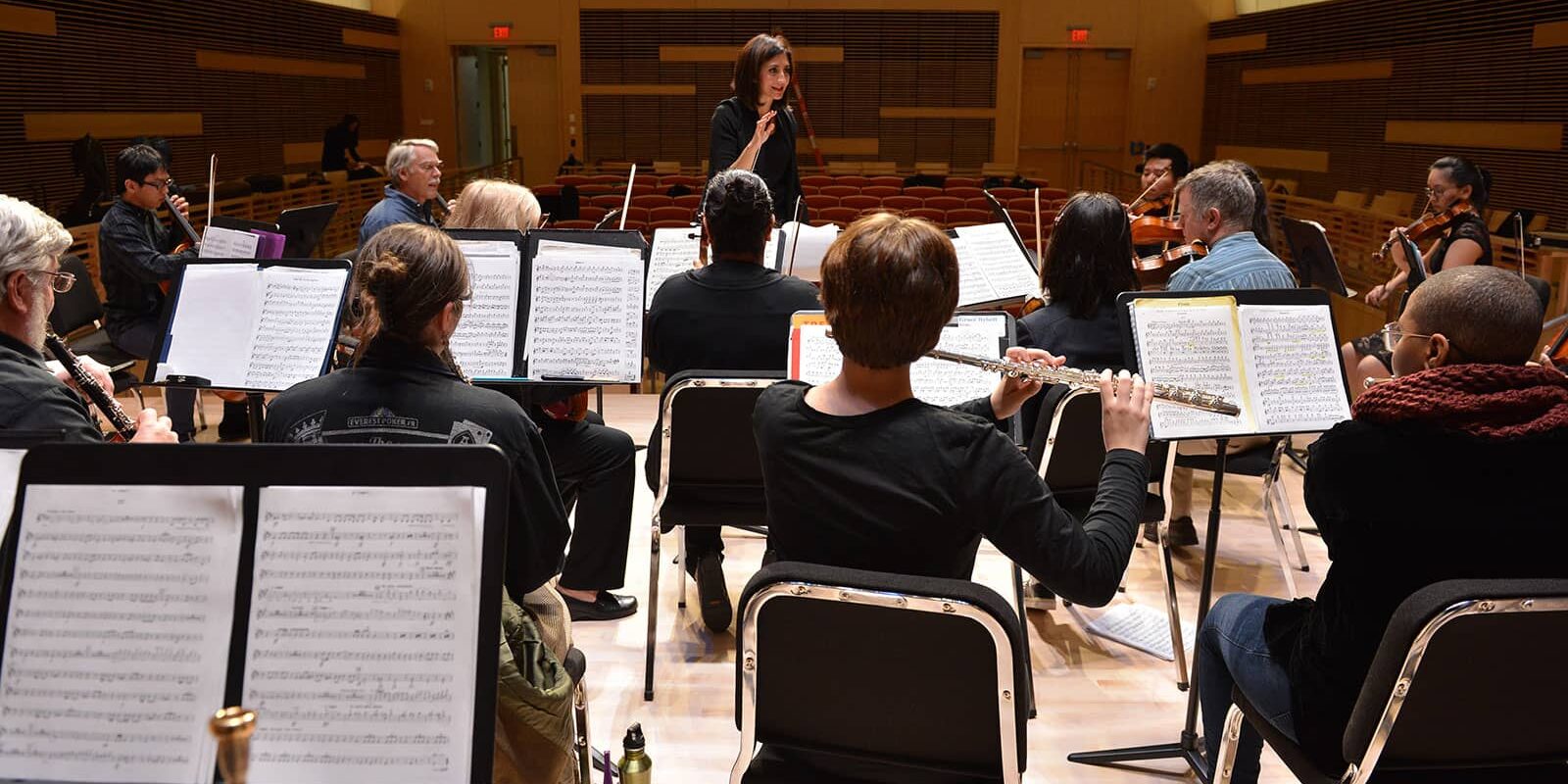 Photo: an orchestra practices on stage.